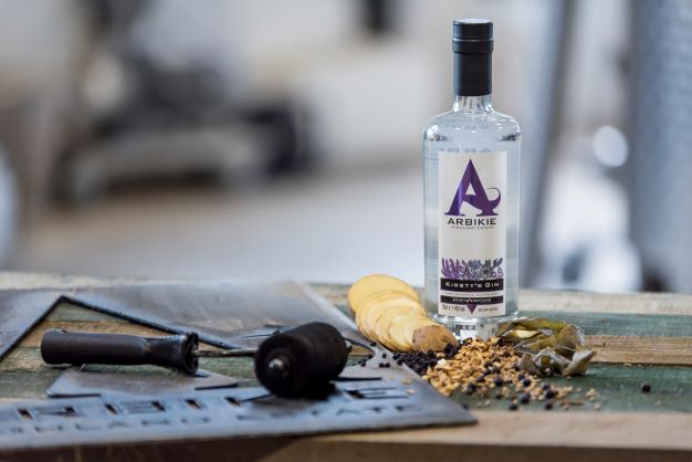 a bottle of kirsty;s gin with botanicals on a counter surface