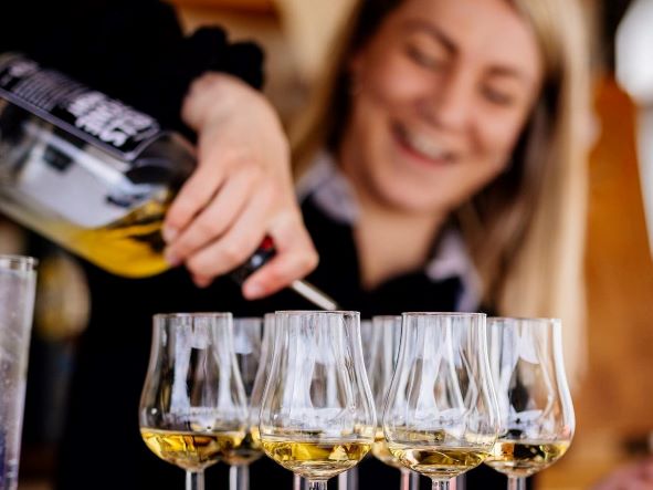 glasses being filled from a bottle of hell's stone whisky by a girl behind a bar