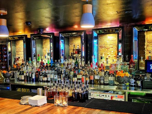 a fully stocked back bar with spirits and cocktail barware