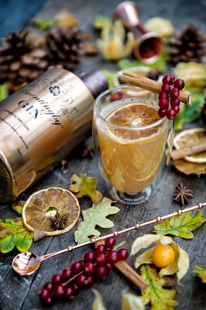 a bottle of brentingby london dry gin with leaves and citrus on a wooden table with a cocktail