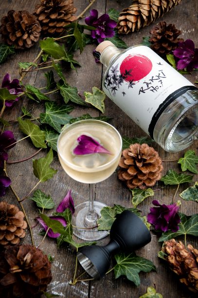 a bottle of rakki gin amongst leaves on a table with a spicy martini cocktail