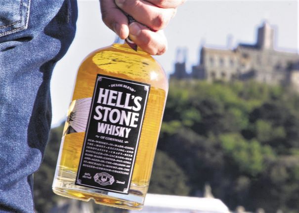 a bottle of whisky being held by a man with a castle in the background