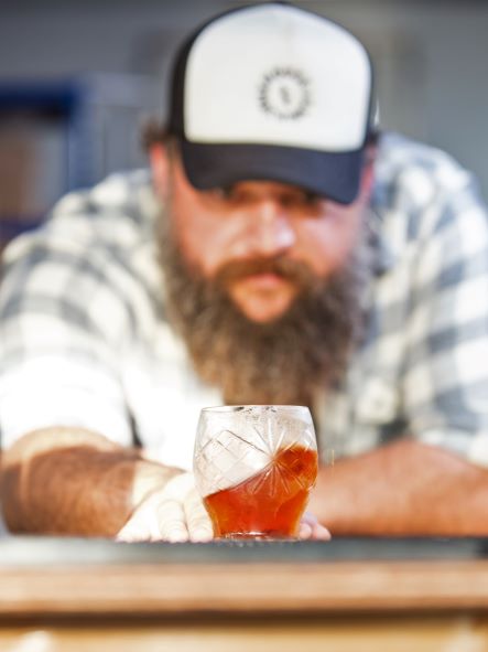 shaun leader of pocketful of stones in the distillery with a cocktail