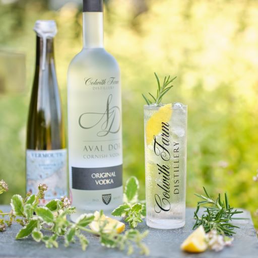 A BOTTLE OF VODKA AND A VODKA SPRITZ GARNISHED WITH LEMON AND HERBS