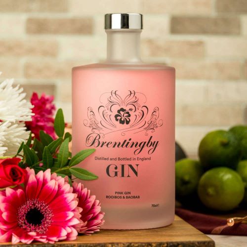 a bottle of pink gin on a table with flowers 