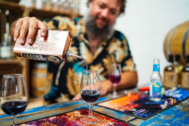 a man pouring drinks behind a bar in a brightly coloured shirt 