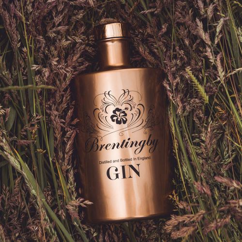 a bottle of brentingby london dry gin sitting on grass