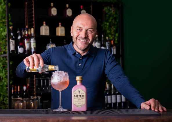 man garnishing a gin and tonic in a kitchen setting